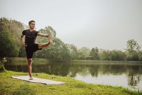 Man doing yoga by the lake